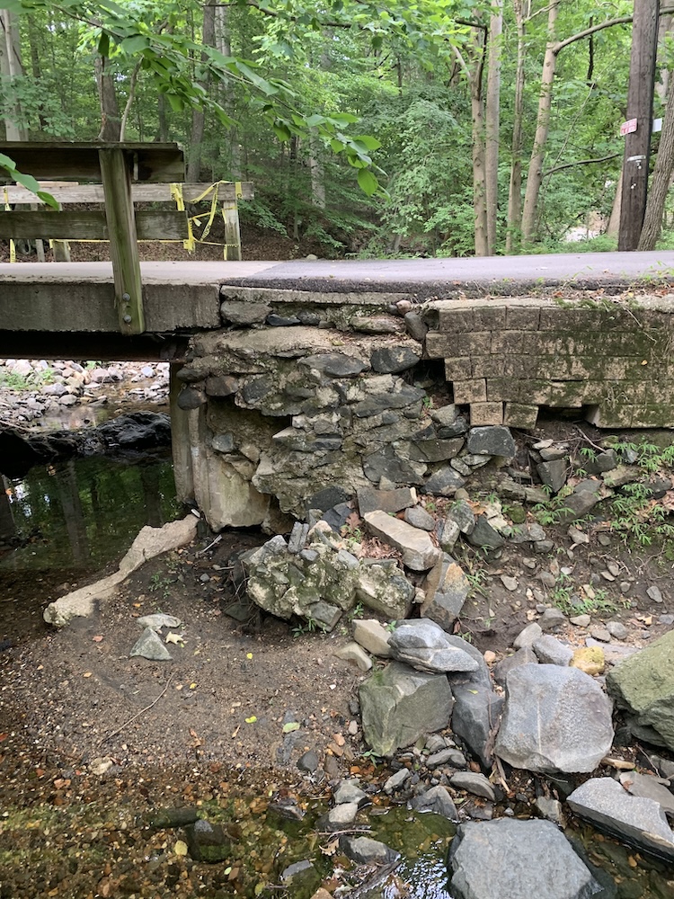 Collapsed concrete abutment wall showing severe erosion