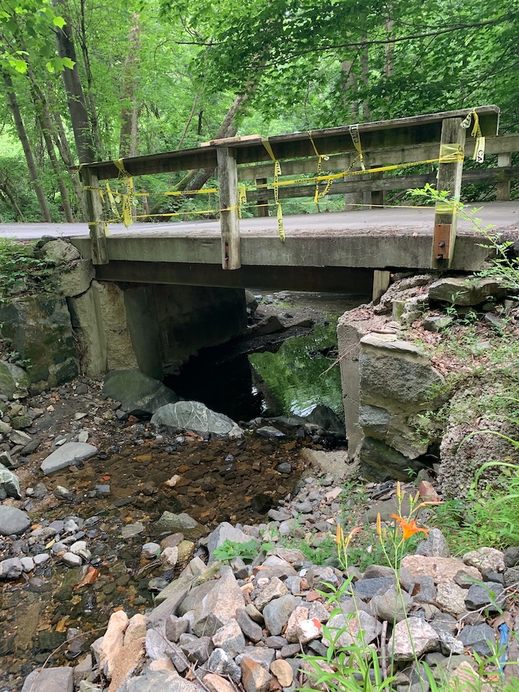 Old bridge with cracked abutments and caution tape