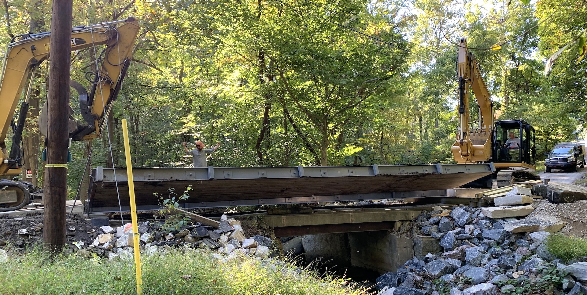 Two excavators lifting and positioning an SL40-12 bridge panel over the existing structure